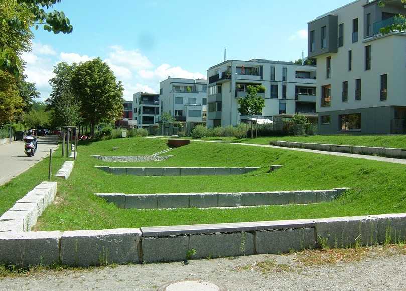 Freiburg im Breisgau, Wohnquartier „Östlich Wiehrebahnhof": Im abschüssigen Gelände liegen leicht vertieft Sickerbeete als ebene Grasflächen, kaskadenartig miteinander verbunden. Die Zuläufe sind als offene Rinnen ausgeführt. | Foto: König Freiburg im Breisgau, Wohnquartier „Östlich Wiehrebahnhof": Im abschüssigen Gelände liegen leicht vertieft Sickerbeete als ebene Grasflächen, kaskadenartig miteinander verbunden. Die Zuläufe sind als offene Rinnen ausgeführt. | Foto: König