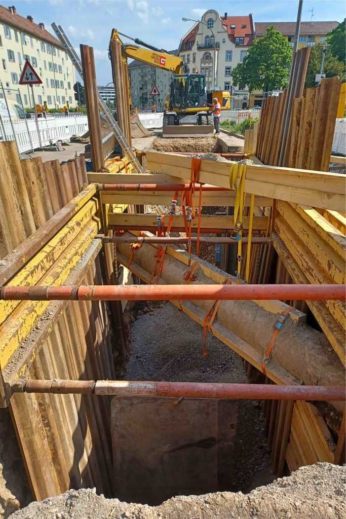Beim Aushub der Baugrube musste das Erdreich teilweise per Hand entfernt werden, wobei die schließlich frei in der Luft hängenden Rohre weiter versteift wurden und schließlich der Verbau einbaut werden konnte. | Foto: Peter Gross Infrastruktur GmbH & Co. KG Beim Aushub der Baugrube musste das Erdreich teilweise per Hand entfernt werden, wobei die schließlich frei in der Luft hängenden Rohre weiter versteift wurden und schließlich der Verbau einbaut werden konnte. | Foto: Peter Gross Infrastruktur GmbH & Co. KG