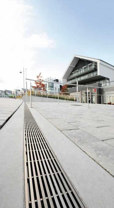 Die von der Promenade aus zu den An- legestellen führenden breiten Rampen werden mit Entwässerungsrinnen trocken gehalten. Die Rinnen sind mit reddot-prämierten Design-Rosten vom Typ Hydra Linearis abgedeckt, die sich durch ihr zeitloses Design gut an die hochwertige Architektur der umliegenden Gebäude anschließen. Die von der Promenade aus zu den An- legestellen führenden breiten Rampen werden mit Entwässerungsrinnen trocken gehalten. Die Rinnen sind mit reddot-prämierten Design-Rosten vom Typ Hydra Linearis abgedeckt, die sich durch ihr zeitloses Design gut an die hochwertige Architektur der umliegenden Gebäude anschließen.