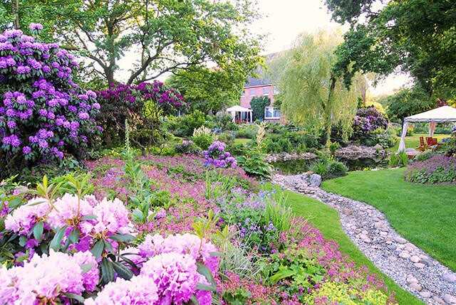 Der Blick in die andere Richtung auf das Haus zeigt die relativ frisch verpflanzten Rhododendren links und die verbesserte Bodenmodellierung samt Trockenbachlauf rund um den neuen Teich. Der Blick in die andere Richtung auf das Haus zeigt die relativ frisch verpflanzten Rhododendren links und die verbesserte Bodenmodellierung samt Trockenbachlauf rund um den neuen Teich.