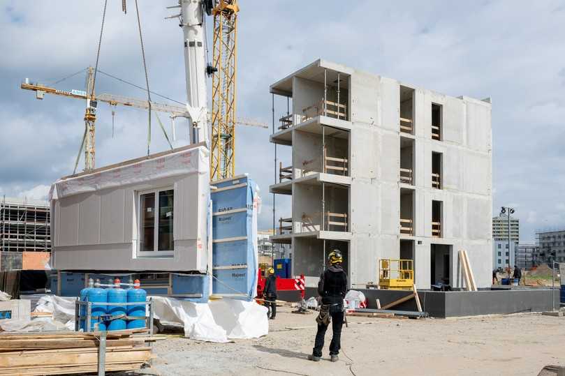 Das erste vorgefertigte Wandelement in Holzrahmenbauweise wird zur Montage versetzt. Rechts der Stahlbetonkern. | Foto: Stadt und Land/Christian Kruppa Das erste vorgefertigte Wandelement in Holzrahmenbauweise wird zur Montage versetzt. Rechts der Stahlbetonkern. | Foto: Stadt und Land/Christian Kruppa