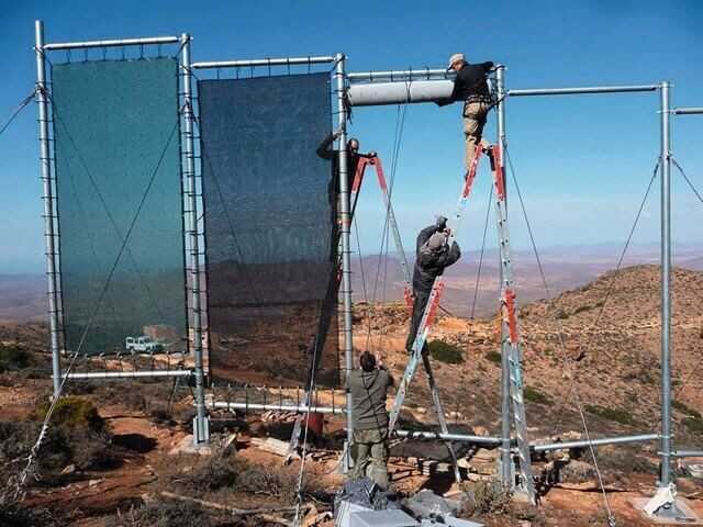 Aus Stahlpfosten und Rohren wird der Nebelkollektor auf dem berg zusammengebaut. Die Nebelsammelnetze werden nach dem Aufbau der Stahlkonstruktion eingesetzt. Aus Stahlpfosten und Rohren wird der Nebelkollektor auf dem berg zusammengebaut. Die Nebelsammelnetze werden nach dem Aufbau der Stahlkonstruktion eingesetzt.